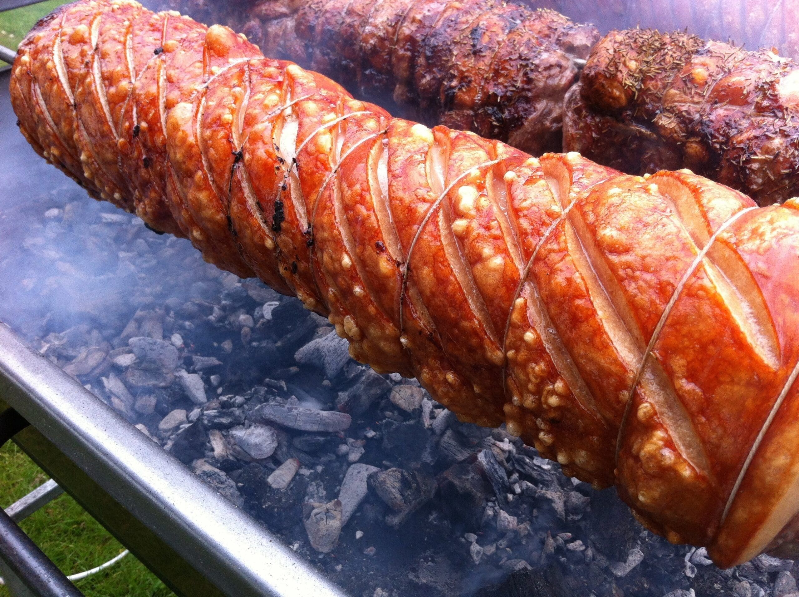 pork loin slowly roasting over charcoal